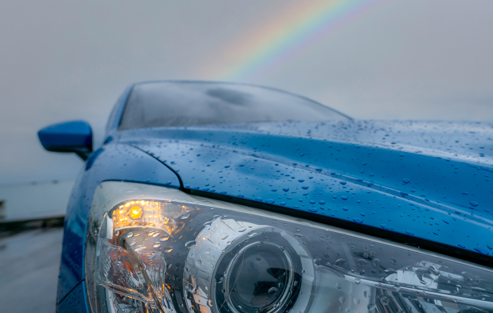 Front view of blue luxury SUV car parked near sea beach on rainy